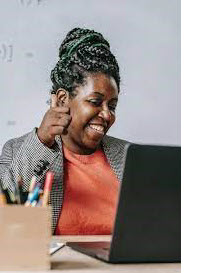 Image of a female teacher at a computer giving students a thumbs up. 