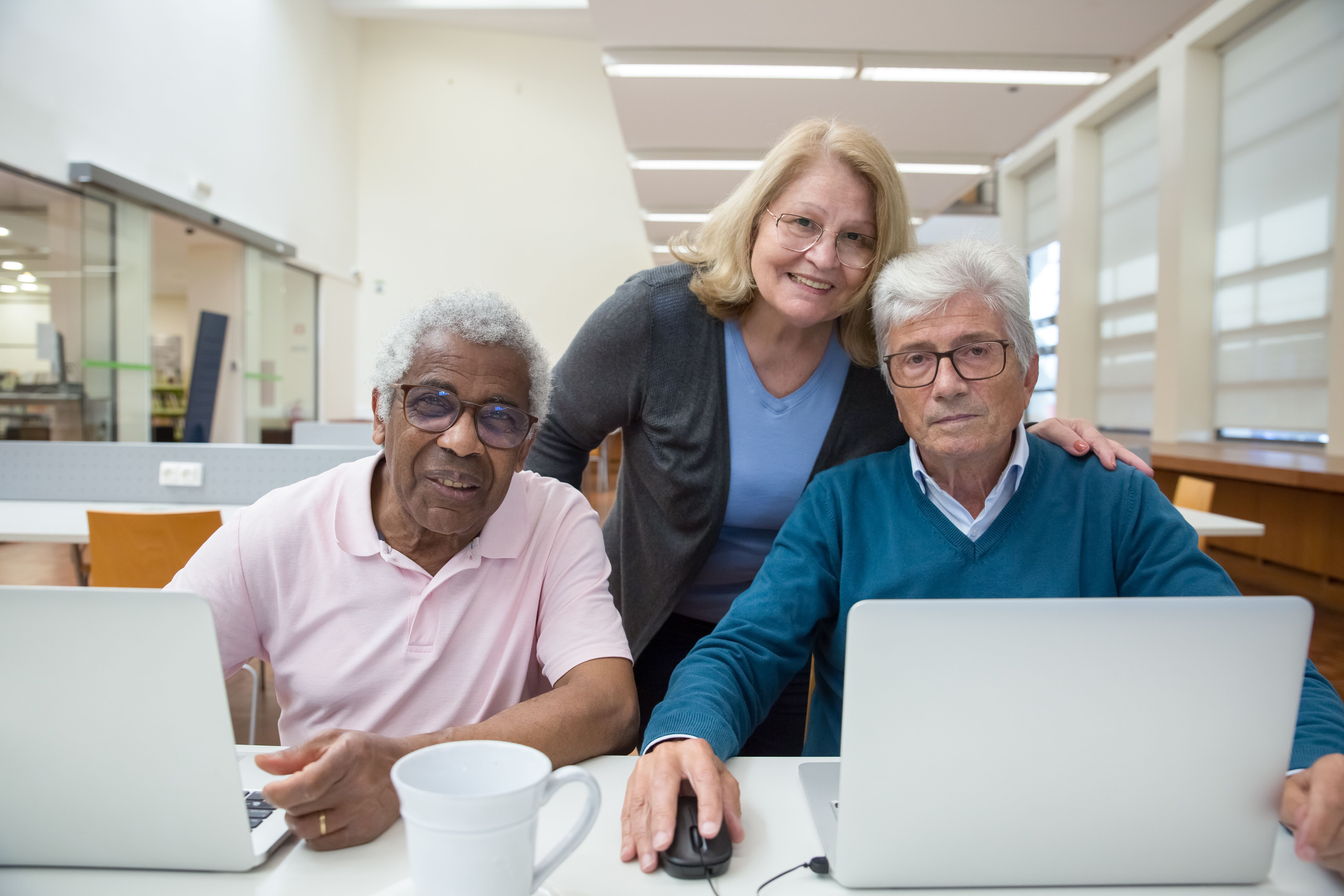 Image of three adults posing for a photo in front of two laptops.