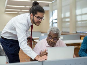 Man helping another man with his computer
