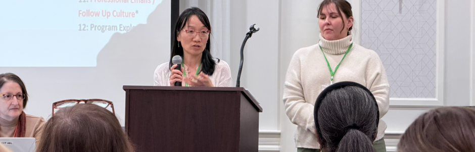 Directors' Meeting 2026 Two women at a podium, one talking, with a third looking on from the side